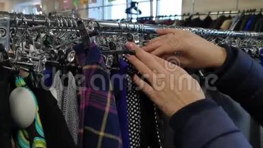 女人在商店里挑选衣服，女人在衣架上`衣服